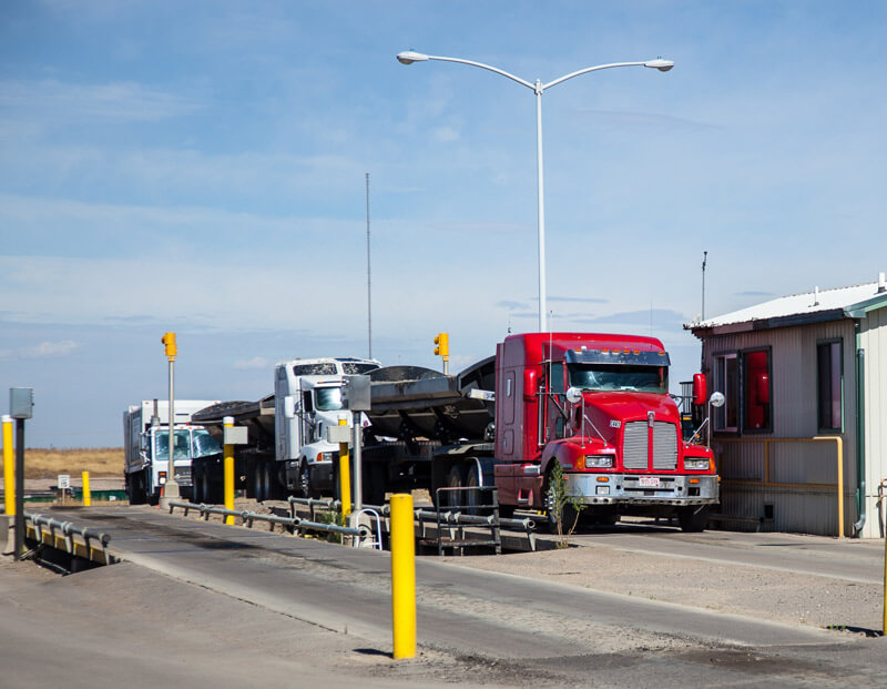 Photo of line of trucks waiting to be weighed on certified scales.
